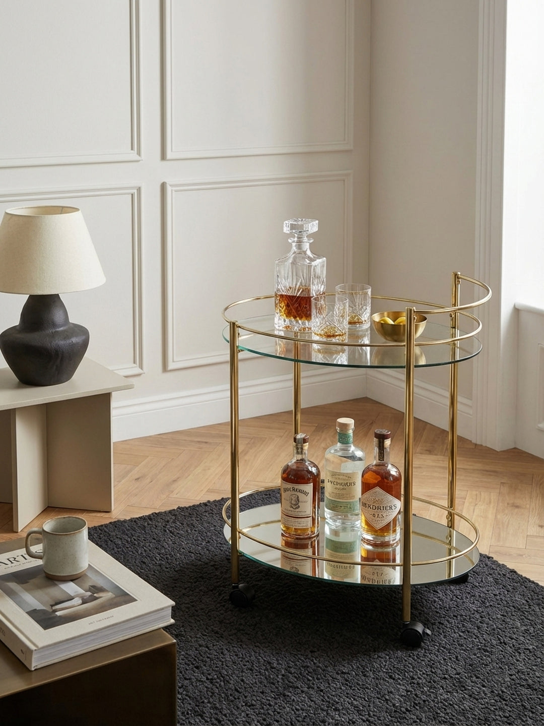Design Barwagen aus Glas und goldfarbenem Stahl von oben betrachtet, zeigt die ovale Form und die Anordnung von Gläsern und Flaschen in einem schicken Interieur._