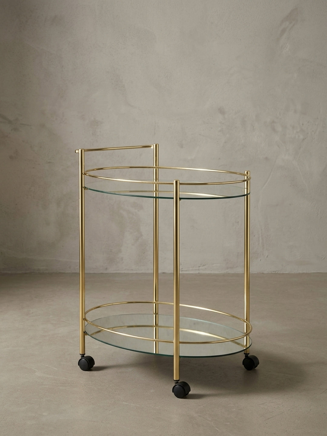 Seitenansicht des Teewagens auf Rollen, die seine schlanken Proportionen mit 79 cm Höhe und das filigrane goldene Gestell aus Stahl zeigt._