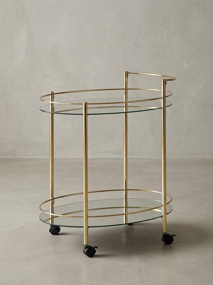 Design Servierwagen aus Stahl und Glas, dessen glamouröse Gold-Optik einen Hauch von Luxus in jede moderne Einrichtung bringt. Mobil dank vier Rollen._