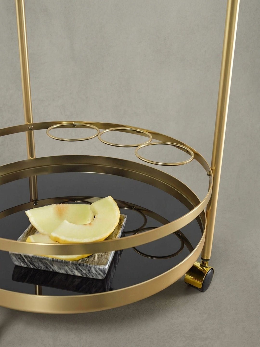 Detailaufnahme des runden Flaschenhalters aus goldfarbenem Stahl, integriert in die untere Ablage des eleganten Speisewagens._