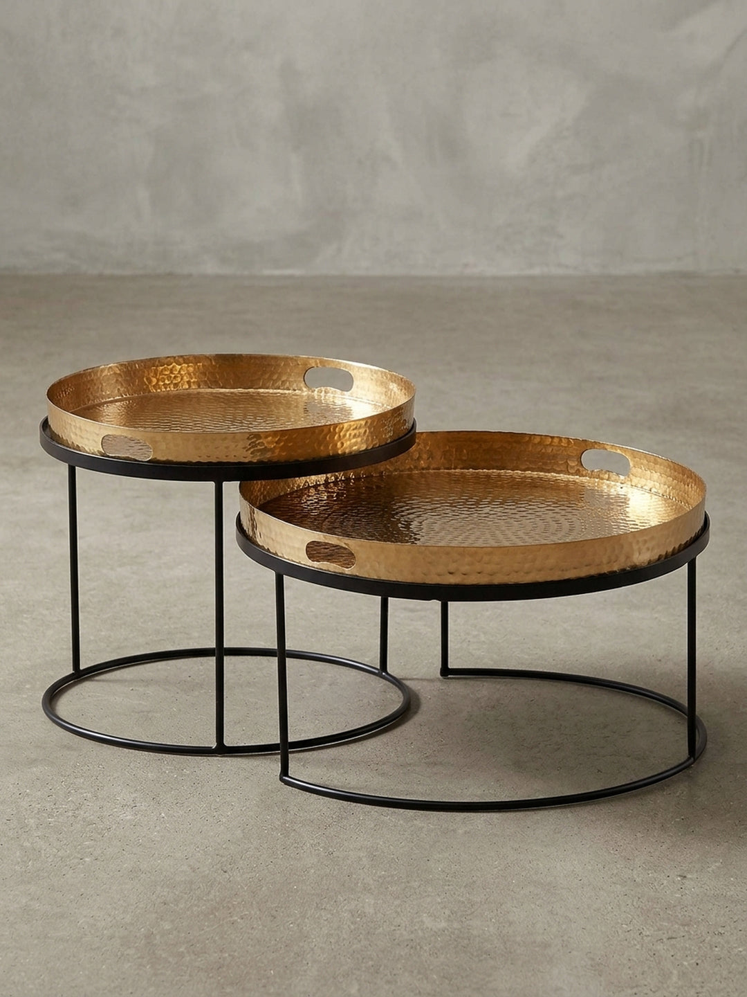 Schräger Blick auf den runden Satztisch aus Metall, der die unterschiedlichen Höhen (41cm und 33cm) und die edle Hammerschlag-Optik der goldenen Tabletts hervorhebt._