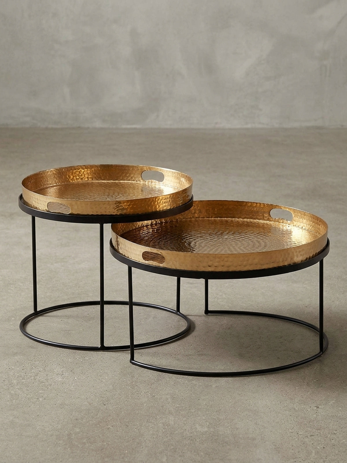 Schräger Blick auf den runden Satztisch aus Metall, der die unterschiedlichen Höhen (41cm und 33cm) und die edle Hammerschlag-Optik der goldenen Tabletts hervorhebt._