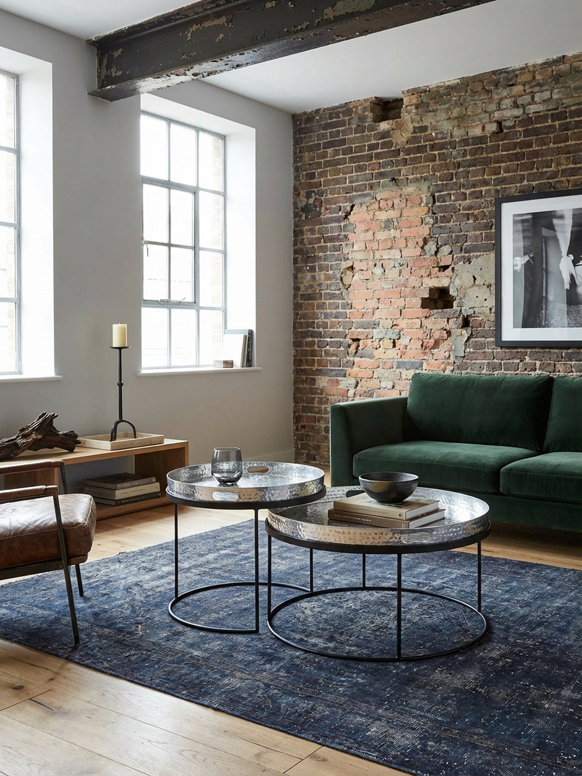 Modernes Couchtisch-Set aus silbernem Metall mit Tabletts im stilvollen Wohnzimmer, platziert auf einem blauen Teppich vor einer grauen Couch._