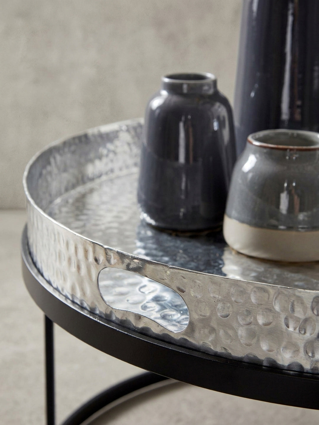 Nahaufnahme der integrierten Griffmulde des silbernen Tablett-Tisches, ein praktisches Detail des modernen Hammerschlag-Designs._