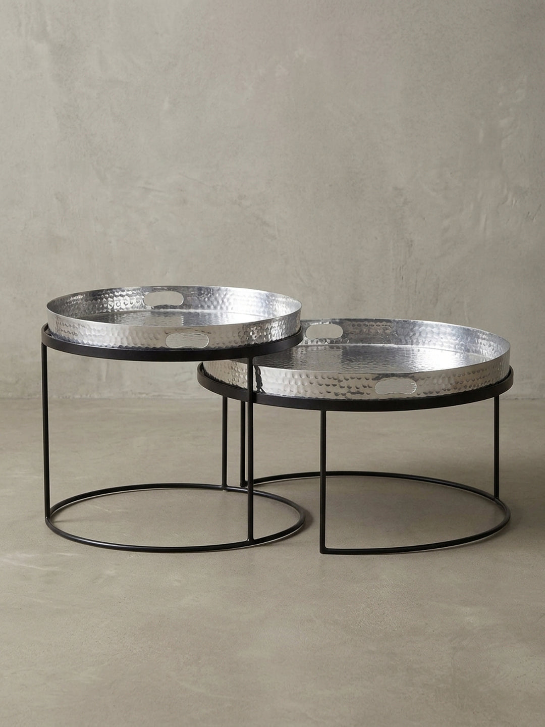 Eleganter Satztisch aus zwei Runden Tischen von der Seite gesehen, zeigt das schwarze Eisengestell und das silberne Tablett mit Griffmulde._