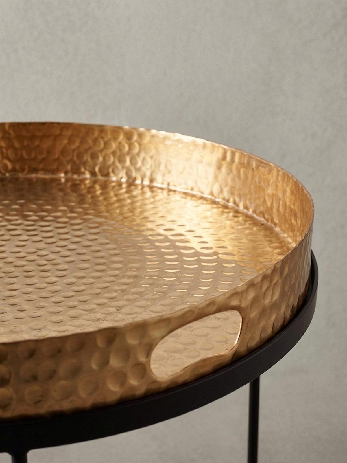 Nahaufnahme des praktischen Griffausschnitts im goldenen Tablett des Sofatischs, ein Detail, das Design und Funktionalität des Metall-Couchtischs vereint._