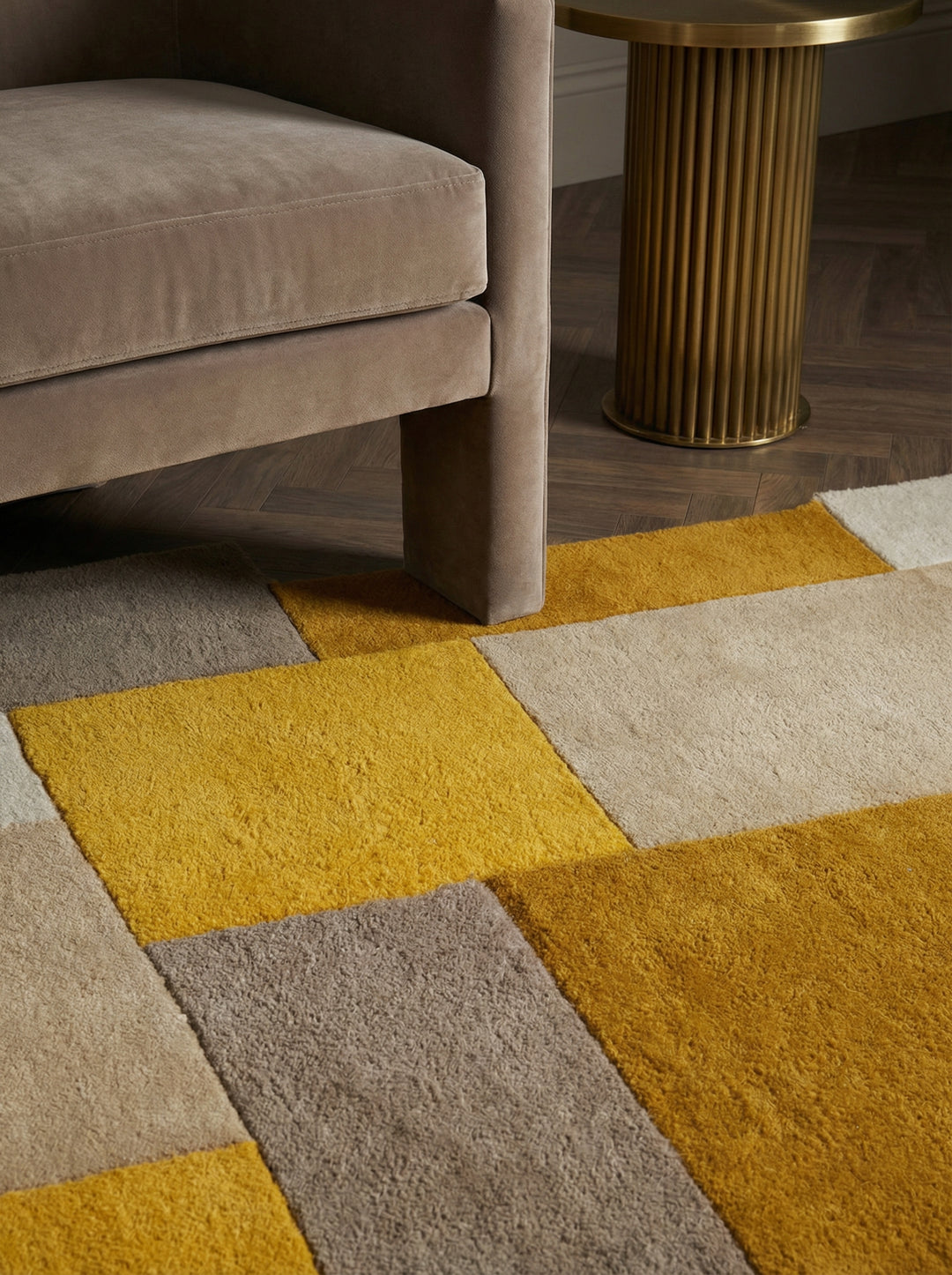 Nahaufnahme und Vollansicht eines handgetufteten Wollteppichs mit gelben und grauen geometrischen Blöcken und unregelmäßiger Kante_