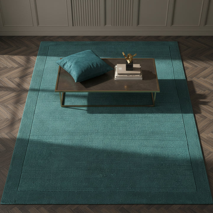 Moderner teal-farbener Teppich auf dunklem Parkett vor einer dunkelblauen Wand_