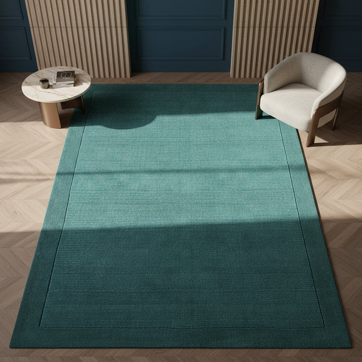 Moderner teal-farbener Teppich auf dunklem Parkett vor einer dunkelblauen Wand_