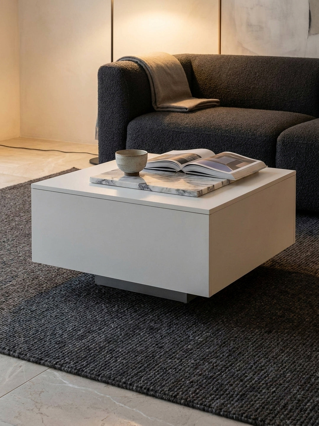 Minimalistischer Sofatisch in Weiß, elegant dekoriert mit einer Calacatta-Marmorschale und einer Tasse Tee vor einer strukturierten Putzwand._