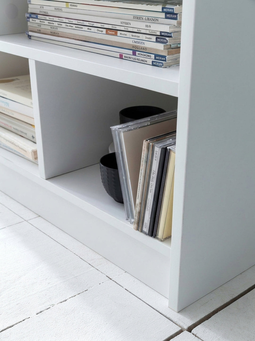Modernes Standregal in Weiß mit 8 asymmetrischen Fächern. Das 80 cm breite und 68,5 cm hohe Bücherregal dient als praktischer Raumteiler im Wohnzimmer oder Büro._