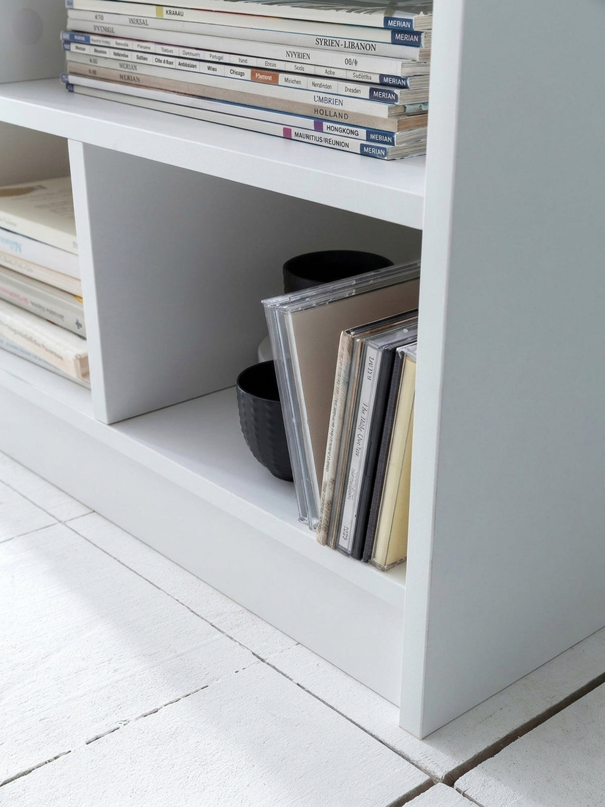 Modernes Standregal in Weiß mit 8 asymmetrischen Fächern. Das 80 cm breite und 68,5 cm hohe Bücherregal dient als praktischer Raumteiler im Wohnzimmer oder Büro._