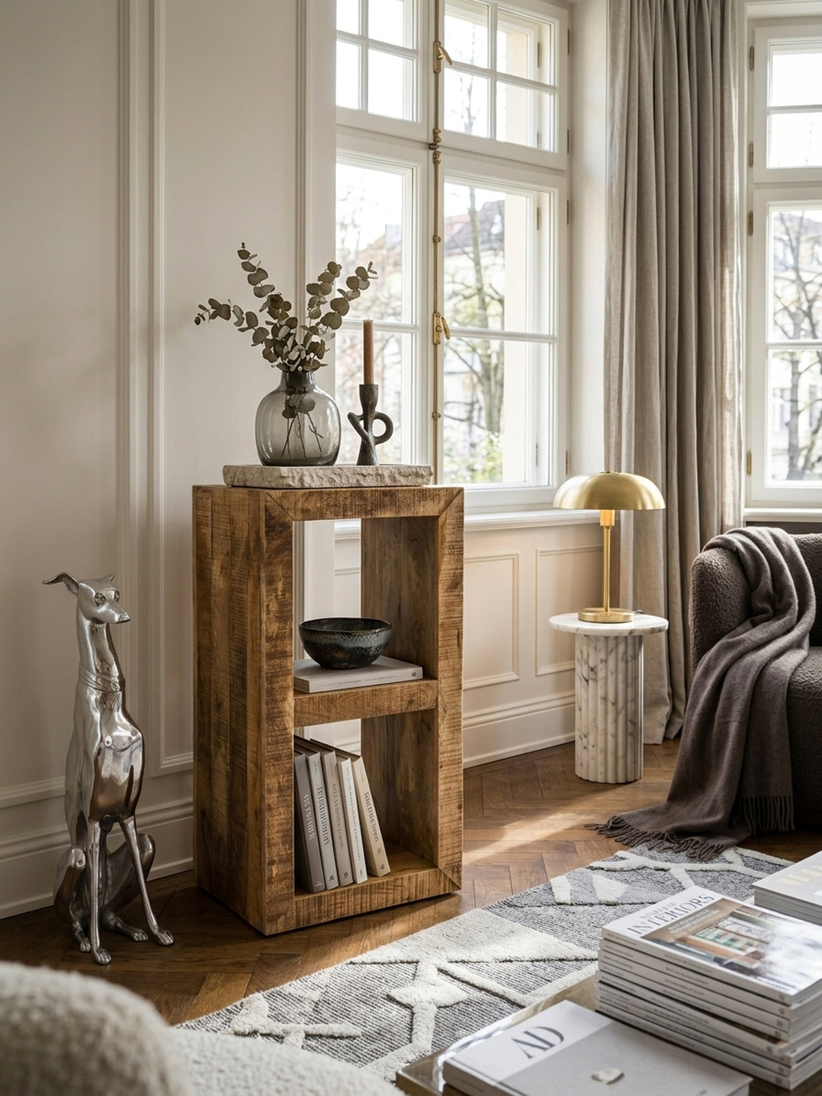 Massivholz Standregal aus Mangoholz im eleganten Wohnzimmer, dekoriert mit Kunstbüchern und Keramik. Das 90x45cm Regal bietet warmen Kontrast zu hellen Wänden._