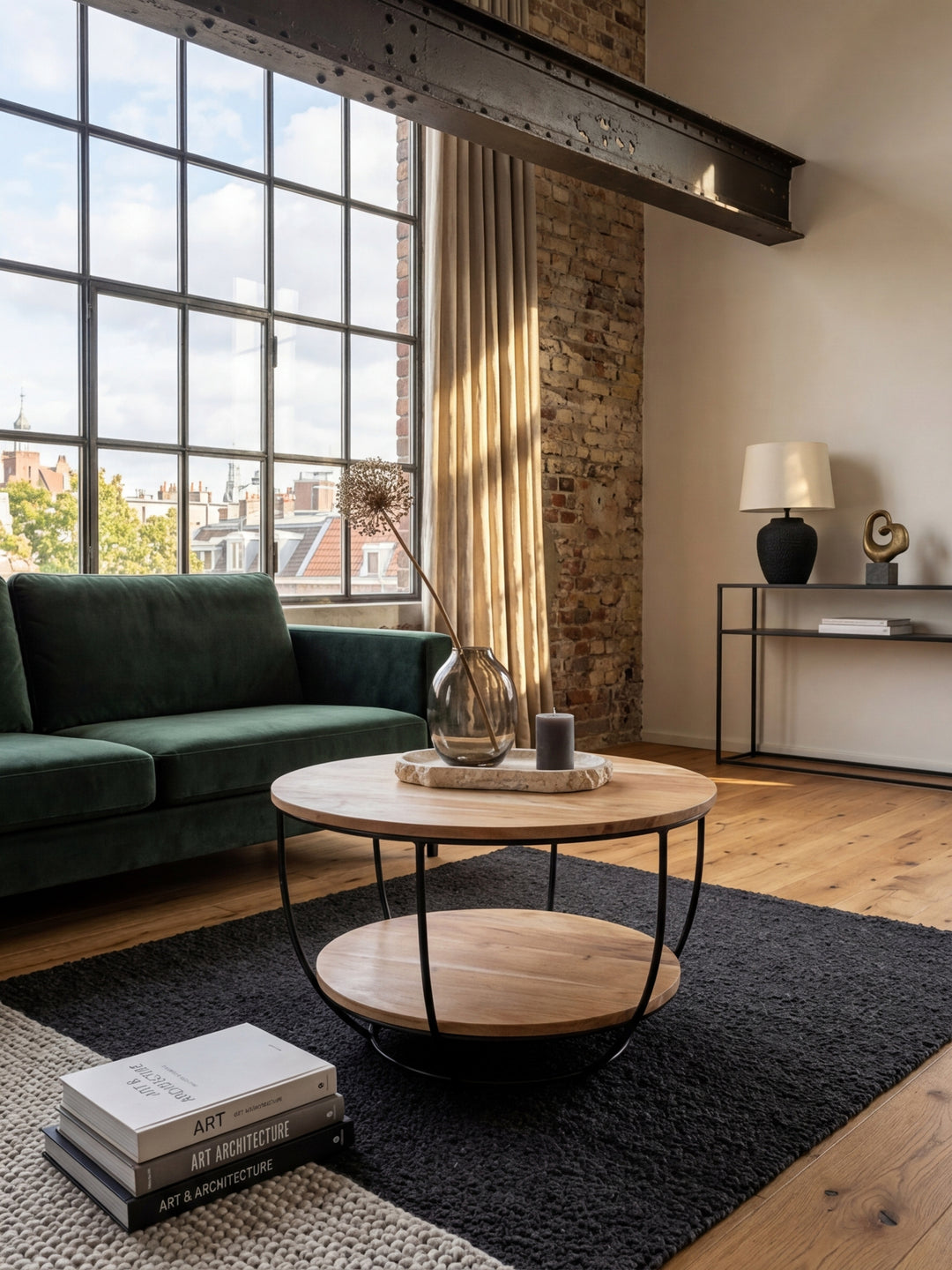 Runder Couchtisch aus Akazie Massivholz mit schwarzem Metallgestell in einem stilvollen Wohnzimmer, dezent dekoriert neben einem grauen Sofa._