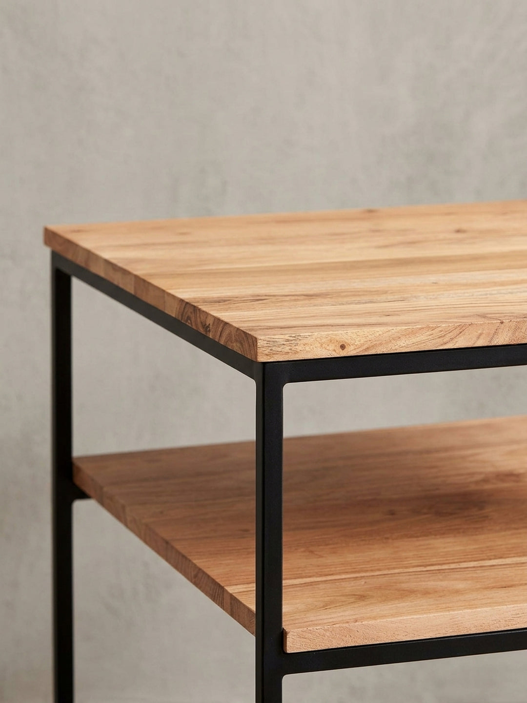 Nahaufnahme der Ecke des Couchtisches, die den präzisen Übergang zwischen der 2 cm starken Akazienholzplatte und dem mattschwarzen Metallrahmen darstellt._