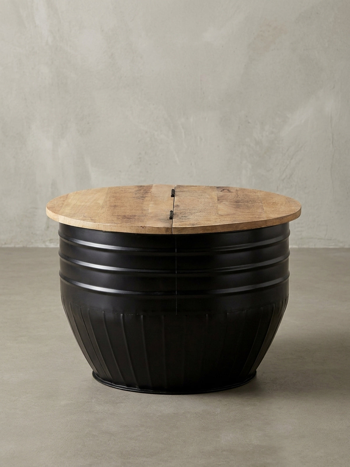 Runder Couchtisch mit schwarzem Metallkorpus und zweigeteilter Mango-Holzplatte vor weißem Hintergrund, Frontansicht des Industrial Designs._