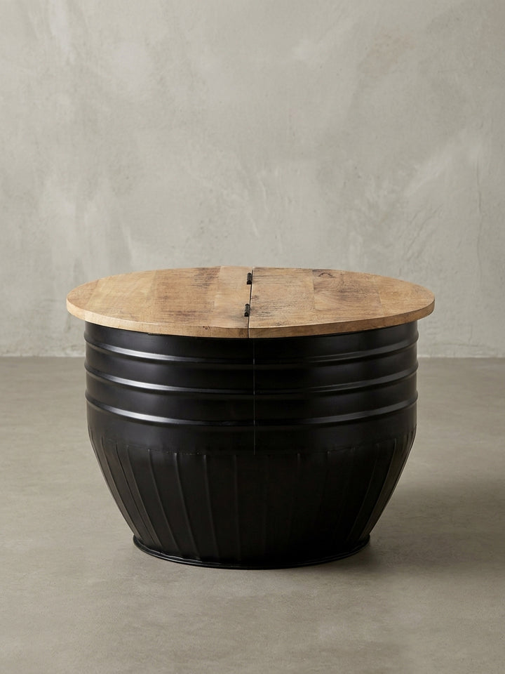 Runder Couchtisch mit schwarzem Metallkorpus und zweigeteilter Mango-Holzplatte vor weißem Hintergrund, Frontansicht des Industrial Designs._