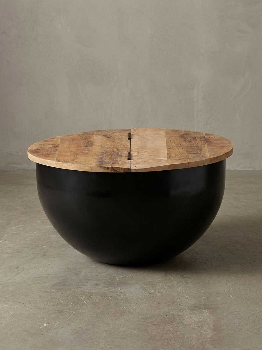 Gesamtansicht des runden Couchtischs im Industrial Style, der die Materialkombination aus warmem Mangoholz und kühlem, schwarz lackiertem Eisen perfekt vereint._