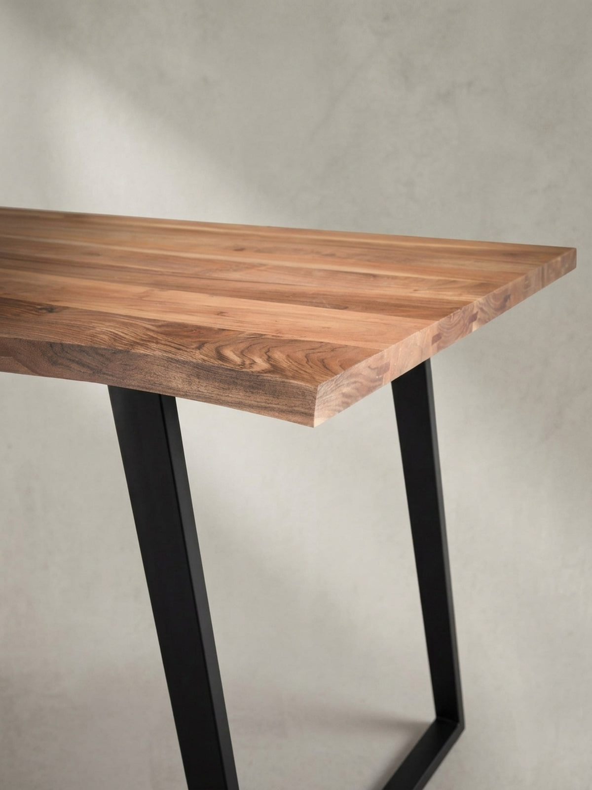 Alternativer Blickwinkel auf den Holztisch, der das Zusammenspiel von natürlicher Holzmaserung und dem mattschwarzen Finish der Metallkufen zeigt._