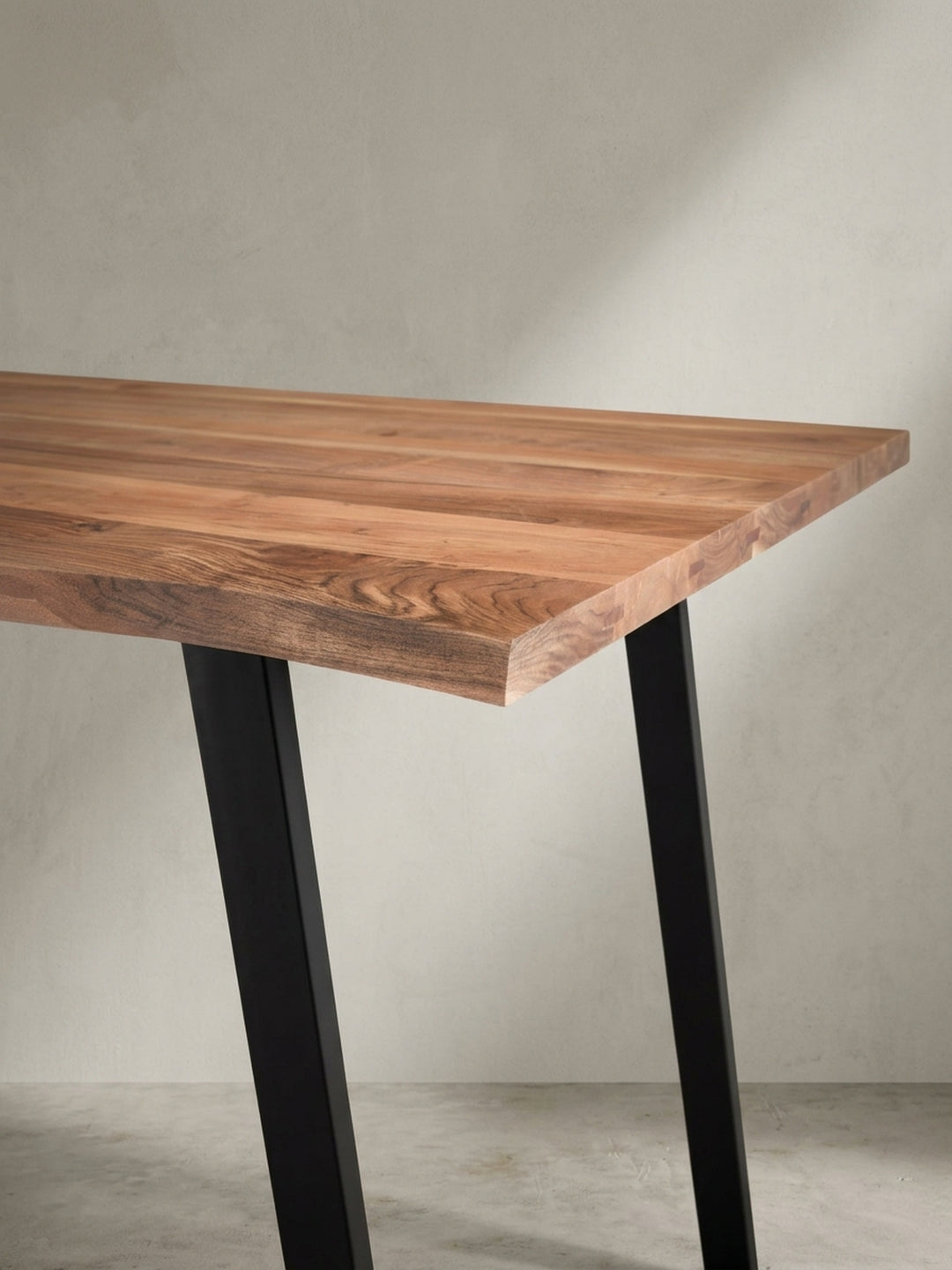 Industrie-Esstisch in einer alternativen Perspektive, die das Zusammenspiel von natürlicher Baumkante und dem geometrischen schwarzen Gestell betont._