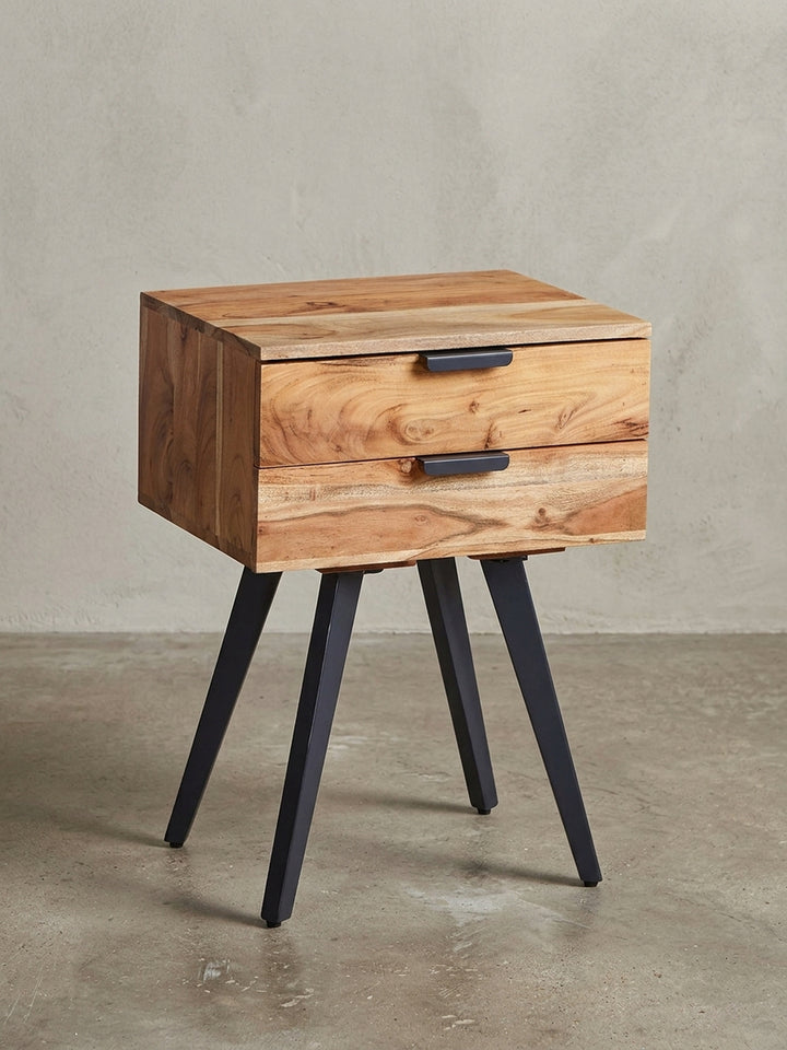 Freigestellte Frontansicht der Nachtkonsole aus Akazie Massivholz, die ihre zwei Schubladen und die schlanken schwarzen Metallbeine zeigt._