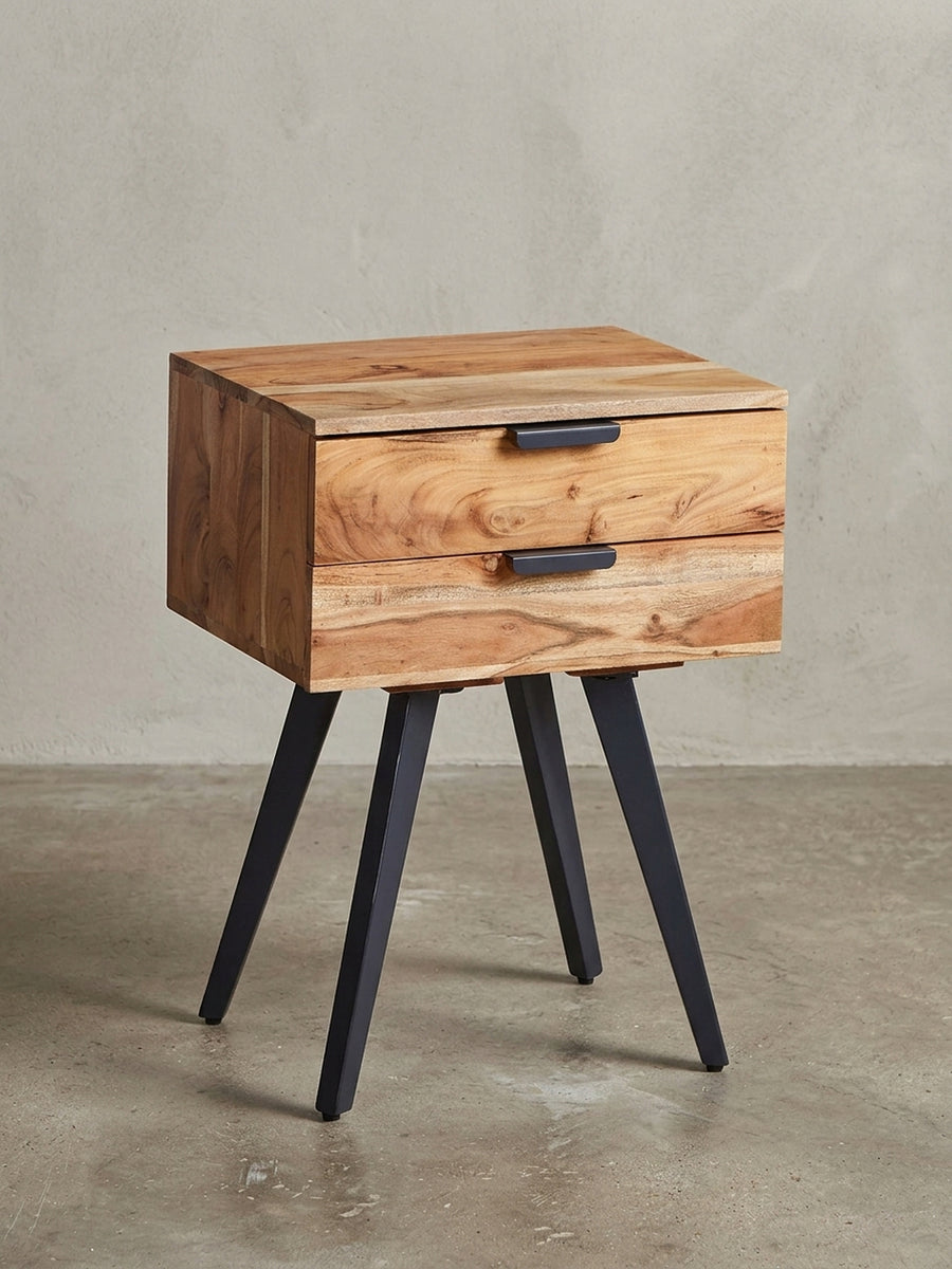 Freigestellte Frontansicht der Nachtkonsole aus Akazie Massivholz, die ihre zwei Schubladen und die schlanken schwarzen Metallbeine zeigt._