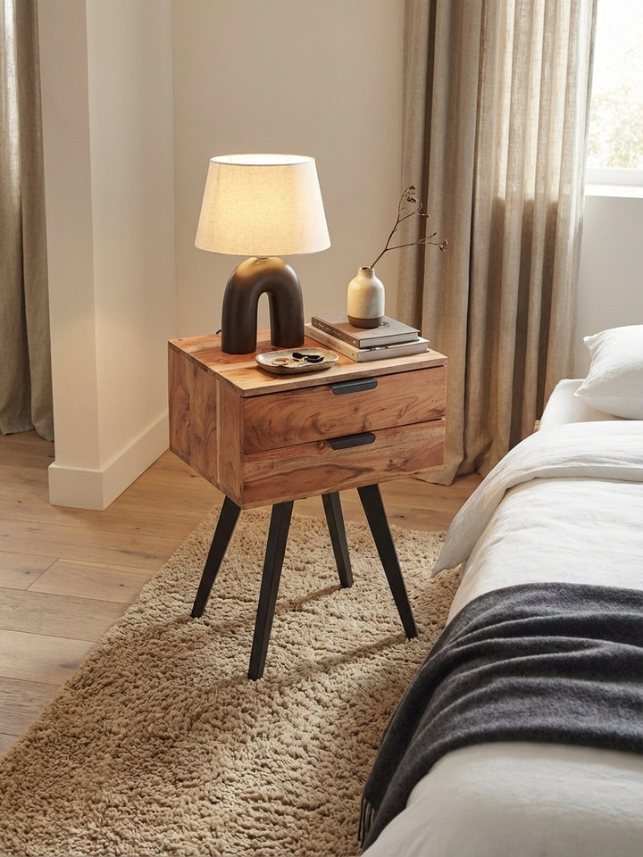 Draufsicht auf die Nachtkonsole aus Akazienholz, die neben einem Bett steht und ausreichend Ablagefläche für eine Lampe und ein Buch bietet._