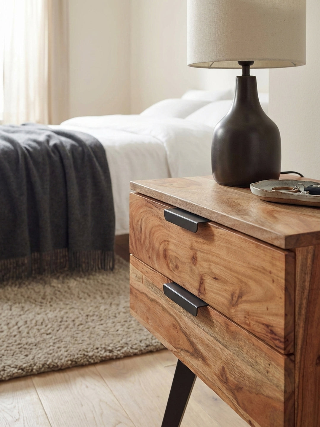 Detailaufnahme der lebendigen Maserung von massivem Akazienholz, das mit Klarlack veredelt ist, auf der Schubladenfront des Nachtkästchens._