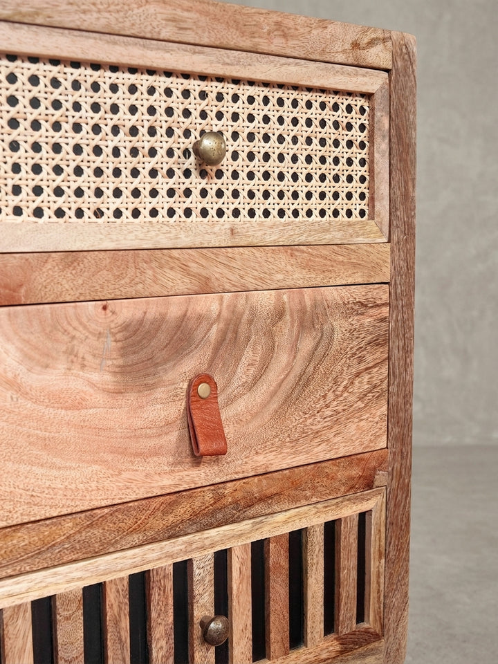 Design-Nachttisch aus einer anderen Perspektive, die die unterschiedlichen Griffe aus Metall und cognacfarbenem Leder hervorhebt._