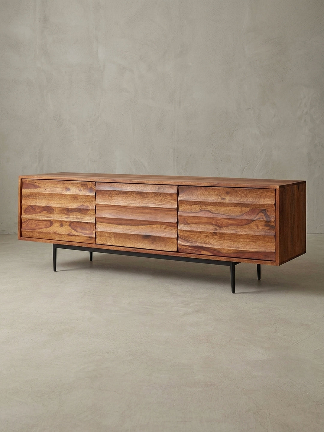 Frontale Ansicht des 147x50x38cm großen Massivholz TV Lowboards im Studio. Die warme rotbraune Farbe des Sheeshamholzes harmoniert perfekt mit dem schwarzen Eisengestell._