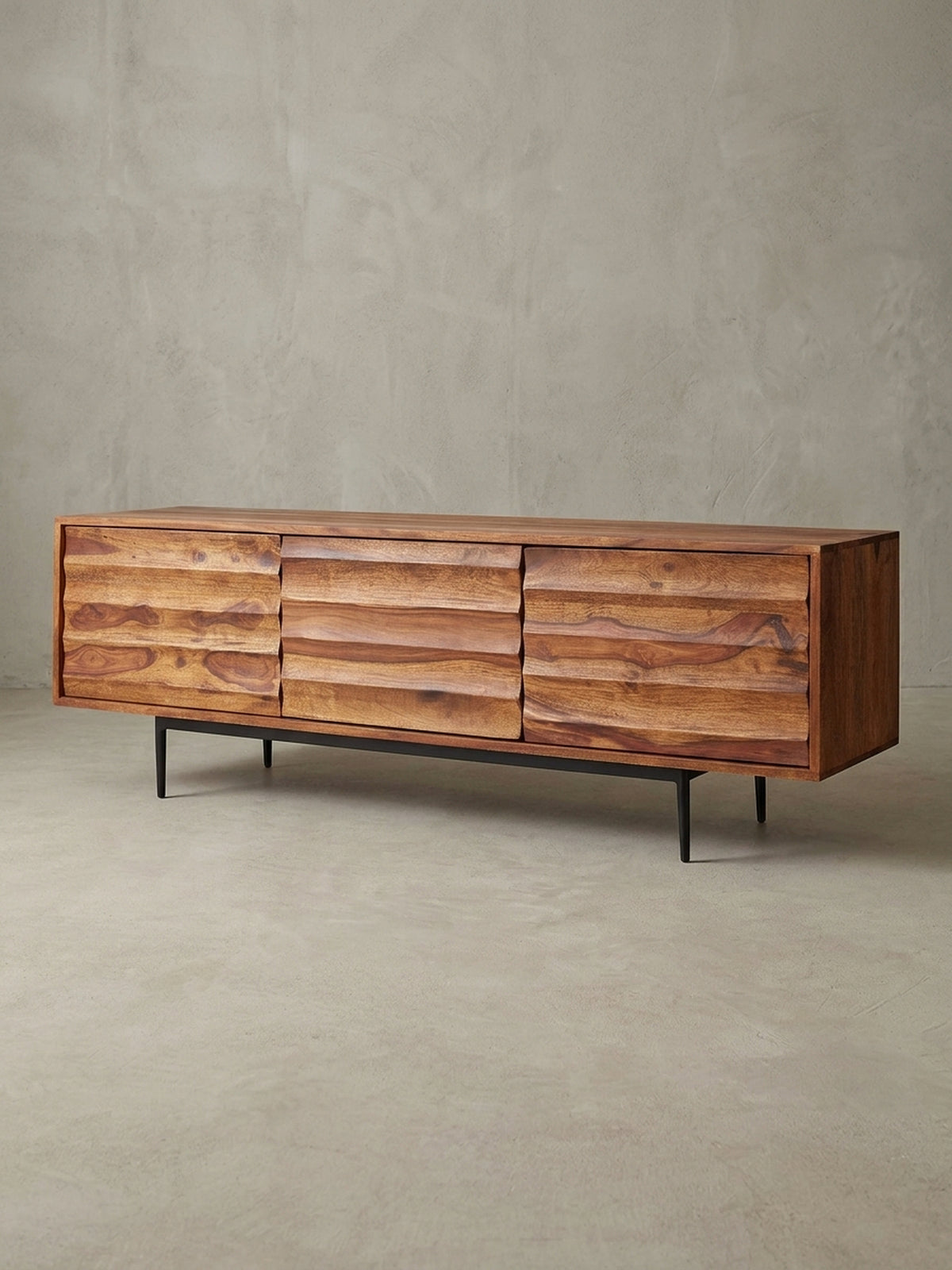 Frontale Ansicht des 147x50x38cm großen Massivholz TV Lowboards im Studio. Die warme rotbraune Farbe des Sheeshamholzes harmoniert perfekt mit dem schwarzen Eisengestell._