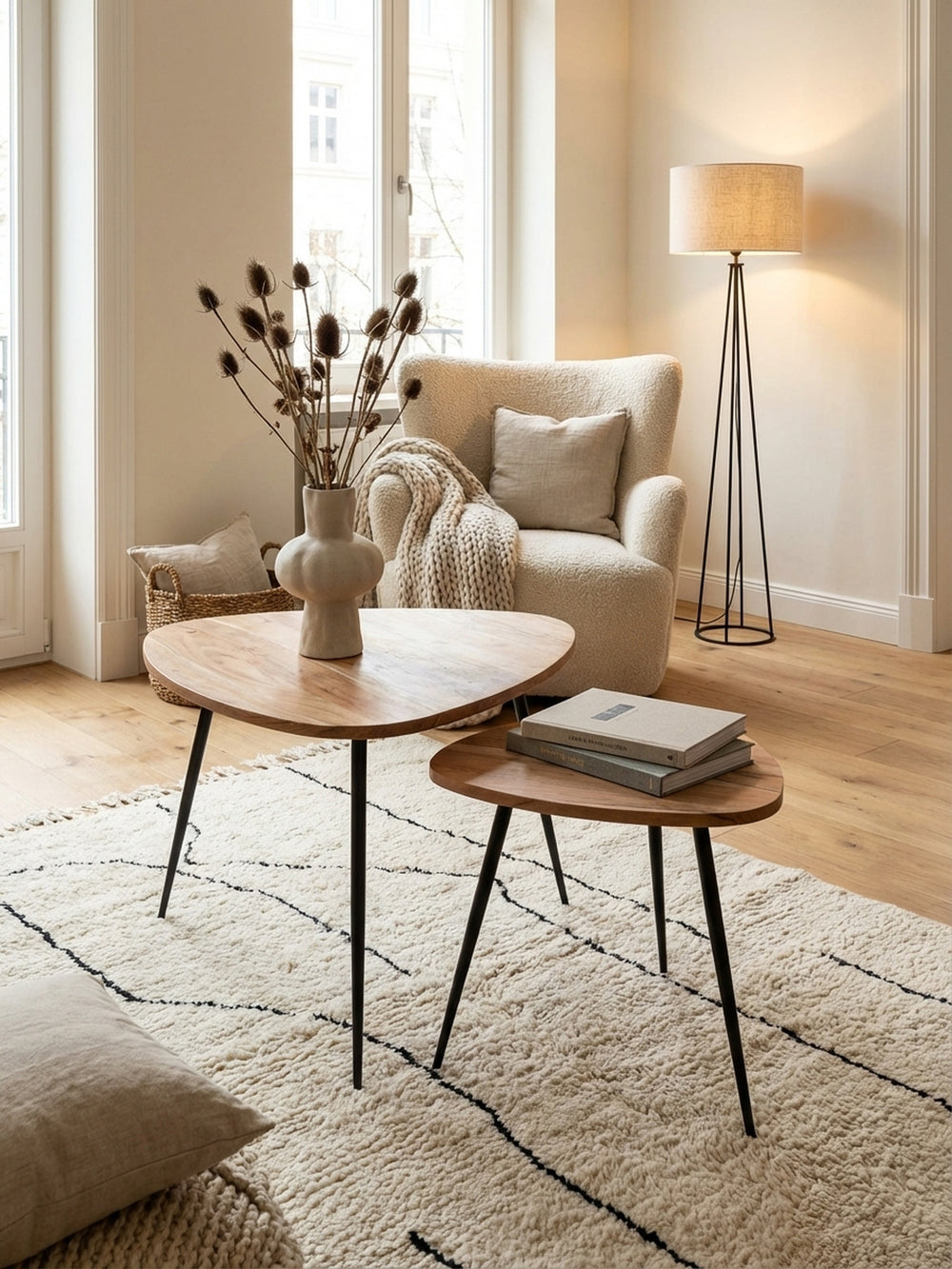 Von oben fotografiertes Beistelltisch-Set aus Holz und Metall, zeigt die Nierenform der Tischplatten und wie die Tische ineinander geschoben neben einem Sofa arrangiert sind._