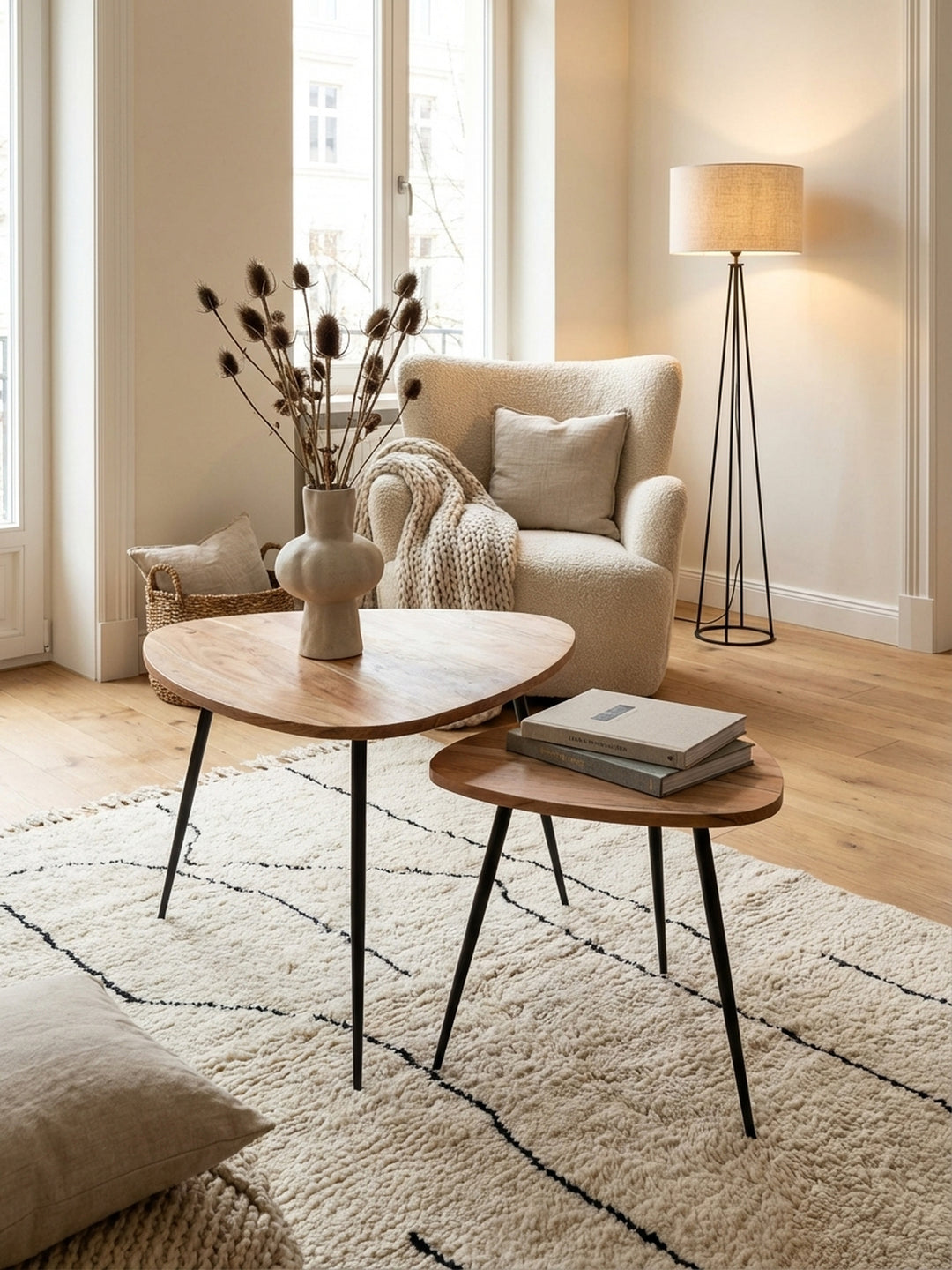 Von oben fotografiertes Beistelltisch-Set aus Holz und Metall, zeigt die Nierenform der Tischplatten und wie die Tische ineinander geschoben neben einem Sofa arrangiert sind._