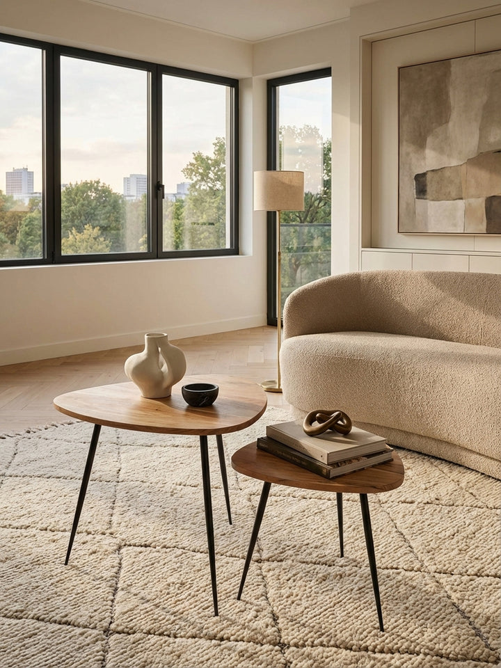 Von oben fotografiertes Beistelltisch-Set aus Holz und Metall, zeigt die Nierenform der Tischplatten und wie die Tische ineinander geschoben neben einem Sofa arrangiert sind._