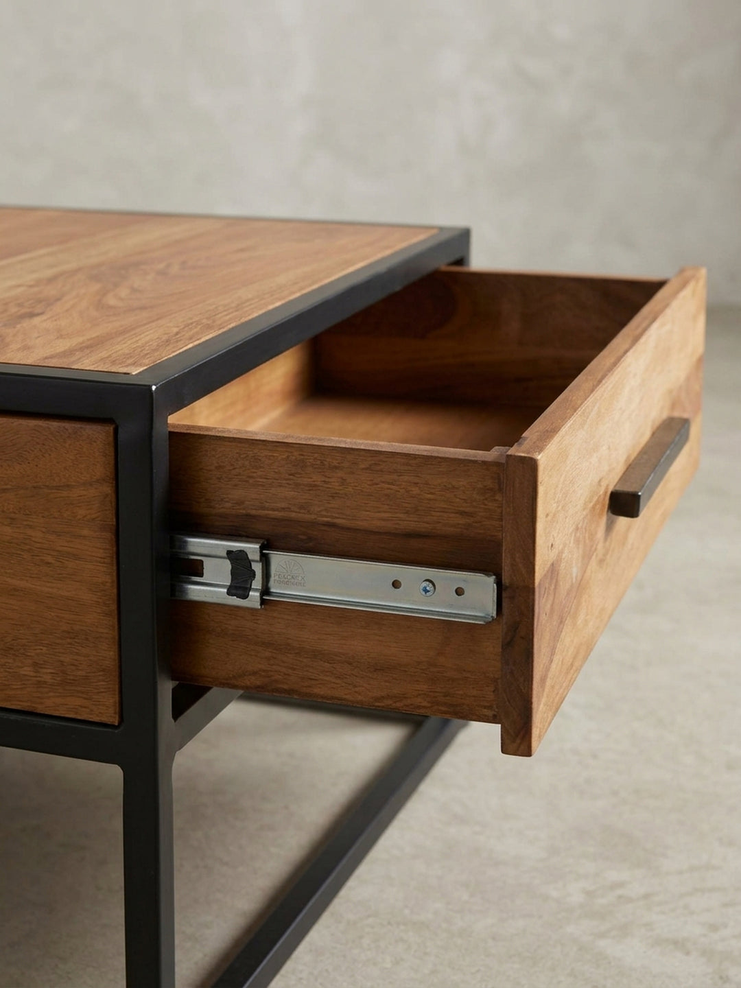 Fokus auf den schwarzen Metallgriff und die Schubladenfront des Couchtisches. Die integrierte Aufbewahrungslösung verbindet minimalistisches Design mit praktischem Nutzen im Alltag._
