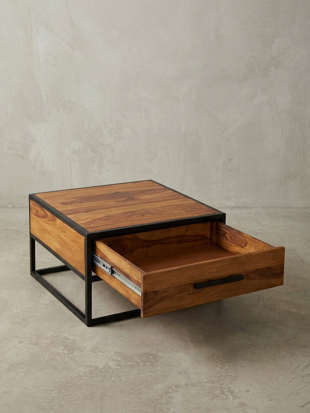 Industrie-Look Couchtisch 65x65 cm aus Echtholz mit einer Schublade. Der quadratische Sofatisch steht auf einem stabilen, schwarzen Metallrahmen und zeigt eine markante Holzmaserung._