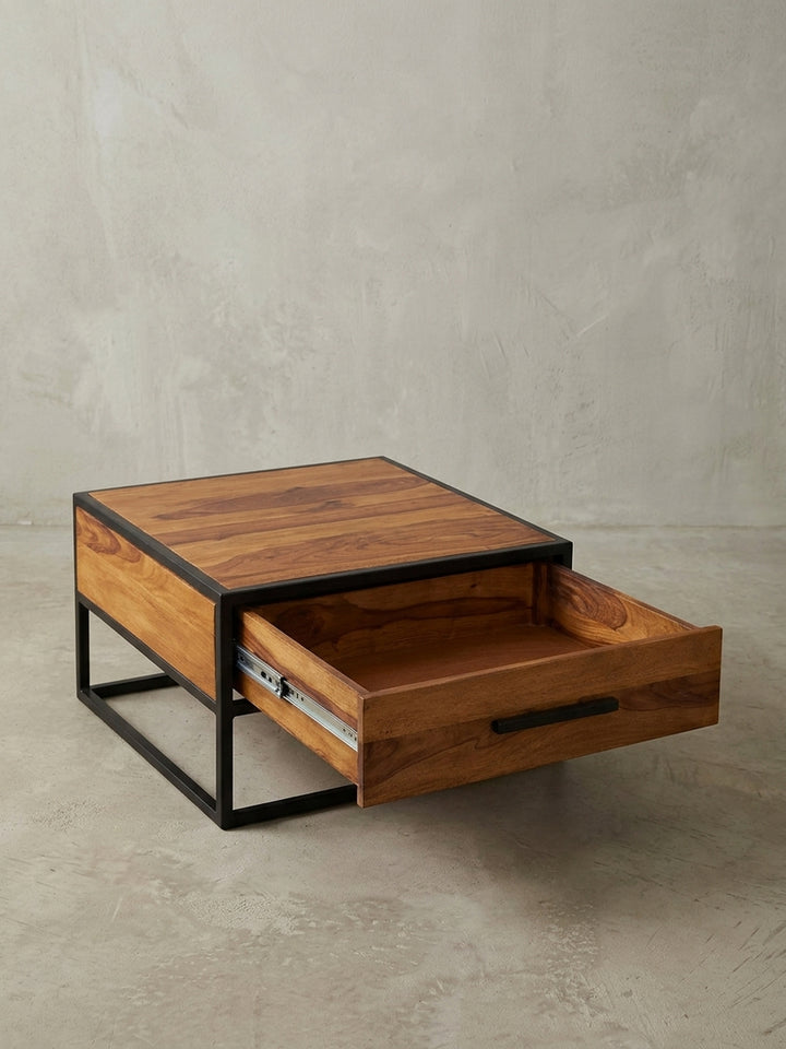 Industrie-Look Couchtisch 65x65 cm aus Echtholz mit einer Schublade. Der quadratische Sofatisch steht auf einem stabilen, schwarzen Metallrahmen und zeigt eine markante Holzmaserung._
