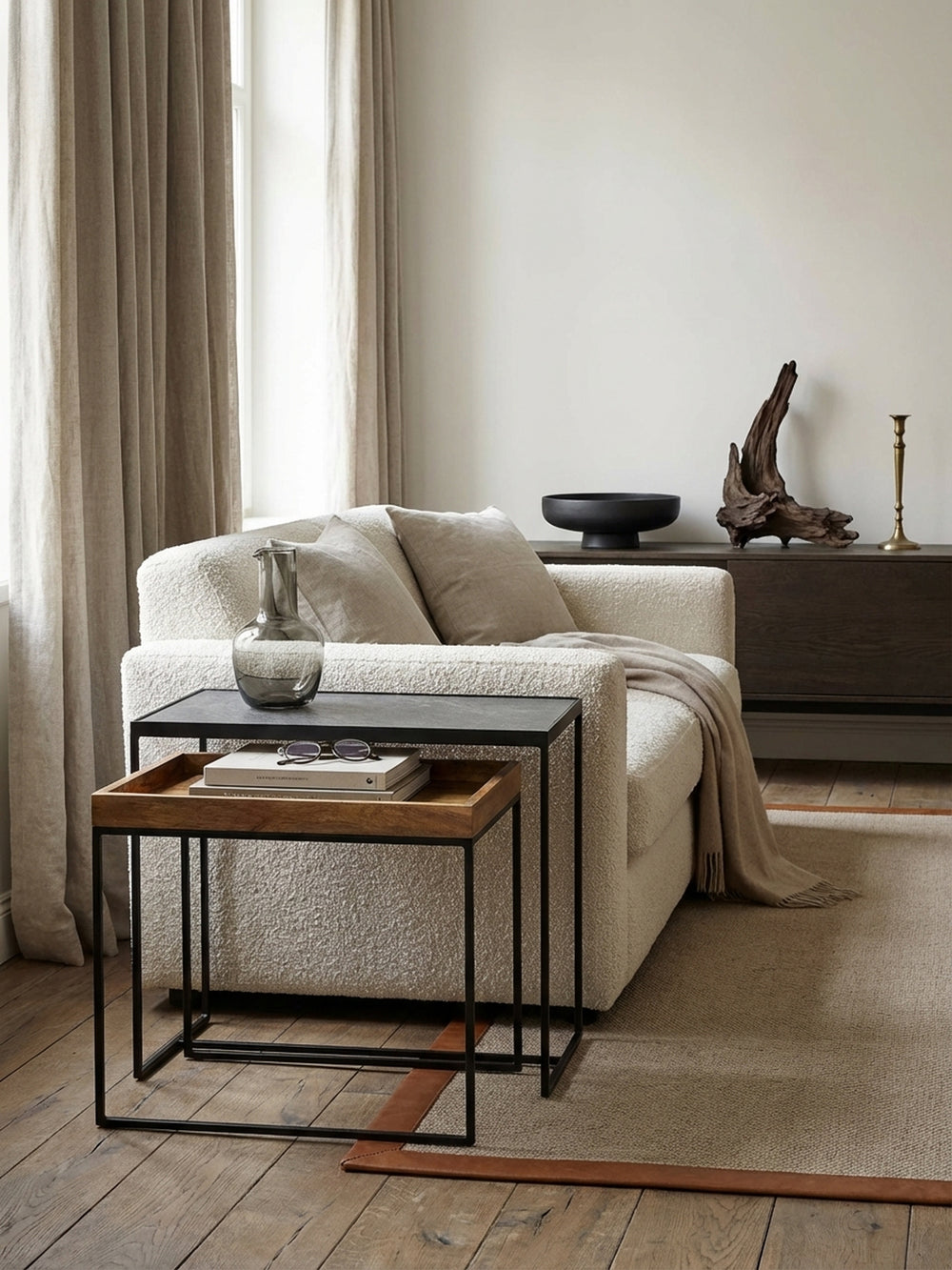 Industrieller Satztisch aus Mango Massivholz und Stein-Optik als Beistelltisch neben einem modernen grauen Sofa in einem stilvollen Loft-Wohnzimmer._