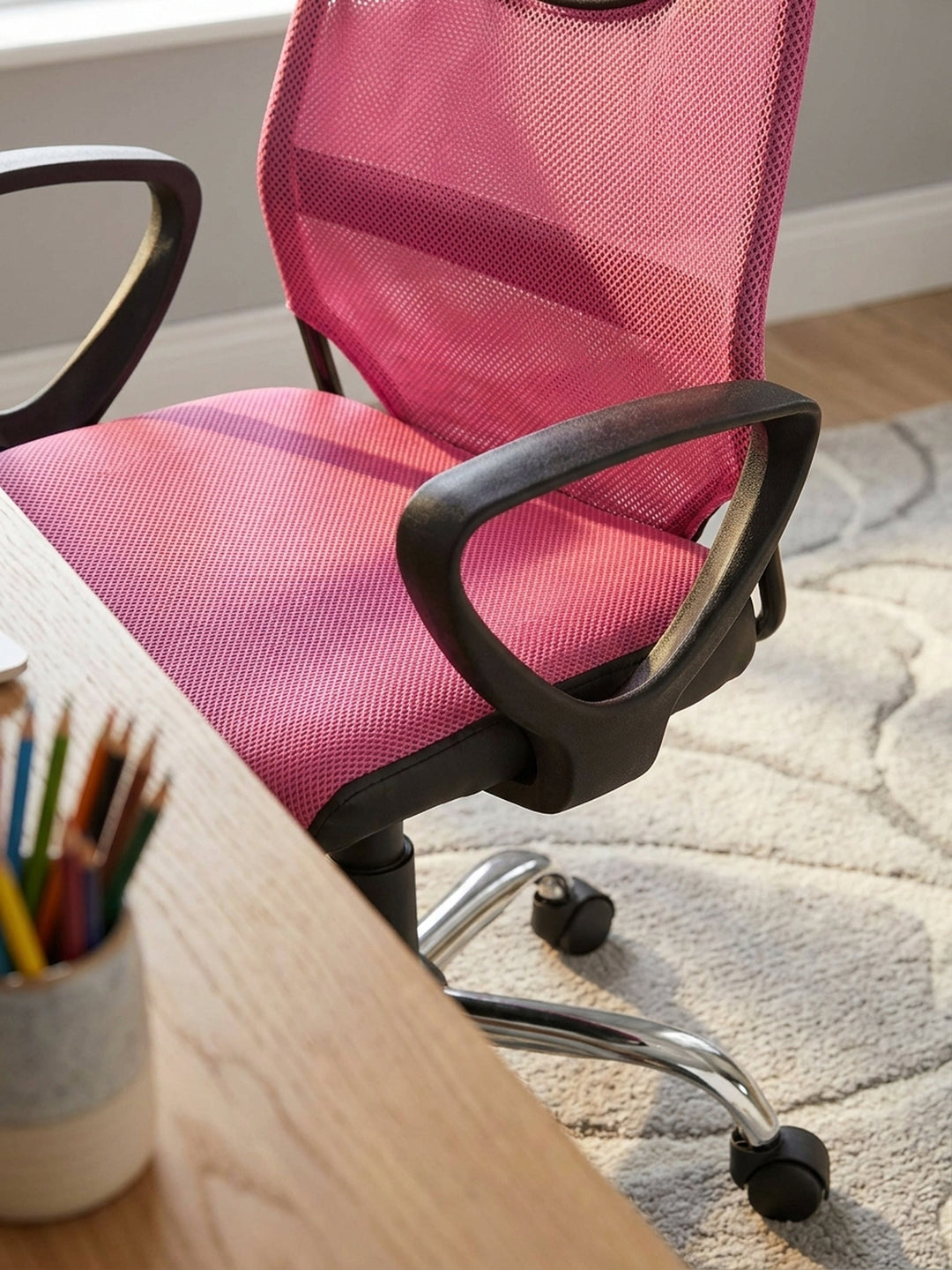Nahaufnahme des pinken Meshbezugs am Kinderdrehstuhl, welche die feine, atmungsaktive Gewebestruktur und die robuste schwarze Kunststoffeinfassung zeigt._