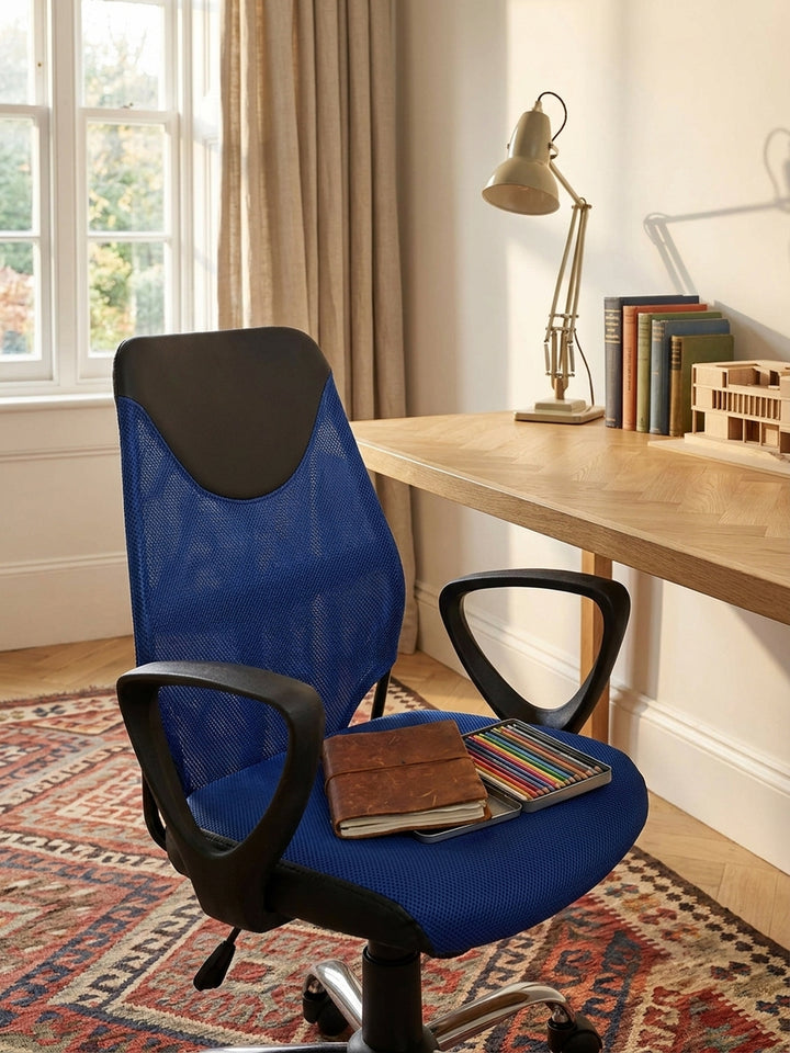 Blaue Sitzfläche des höhenverstellbaren Jugendstuhls an einem aufgeräumten Schreibtisch mit Skizzenbüchern und einer matten weißen Schreibtischlampe._