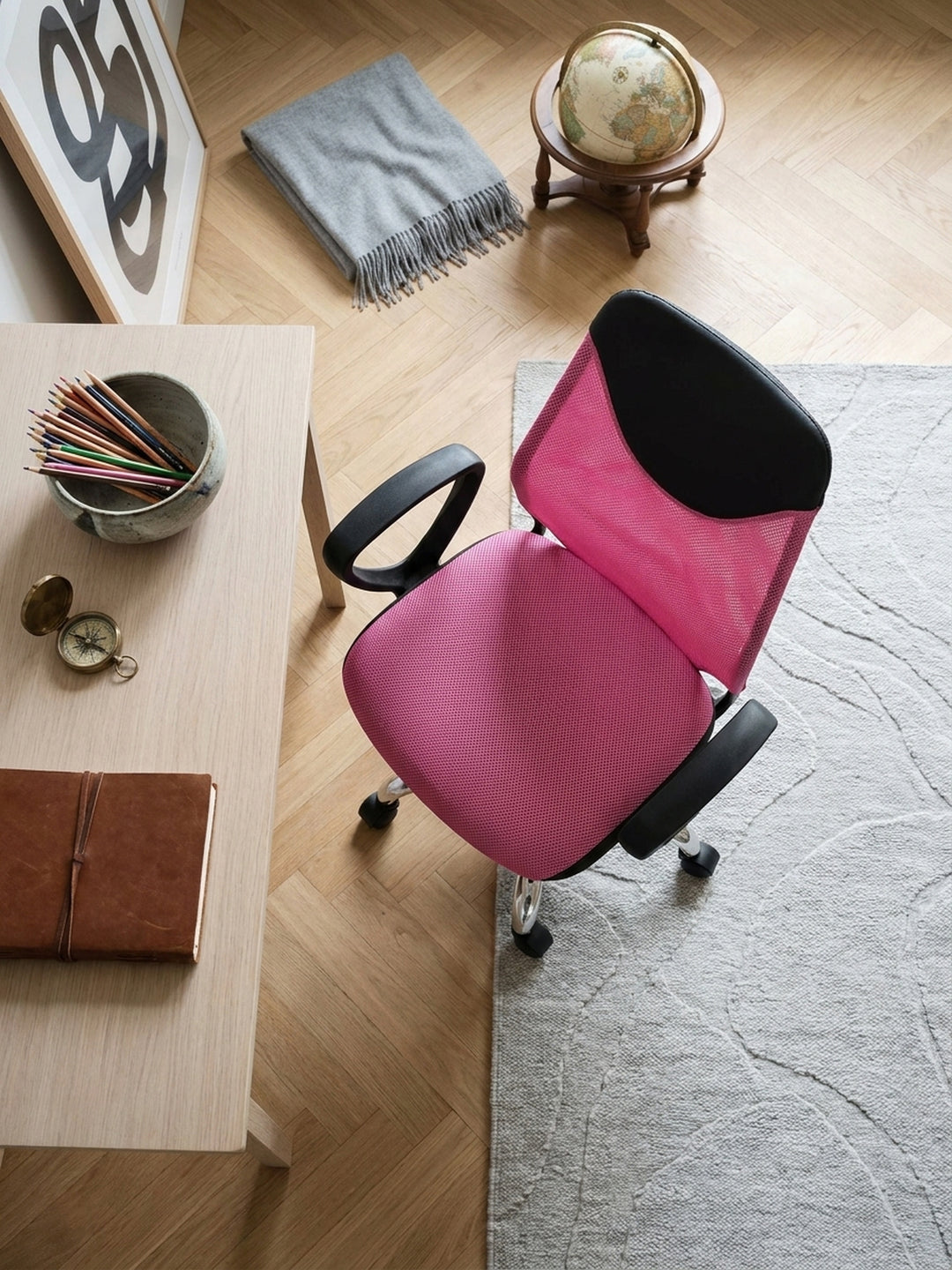 Ergonomischer Kinder-Bürostuhl von oben betrachtet, auf einem hellgrauen Wollteppich neben einem minimalistischen Lernbereich im Altbau platziert._