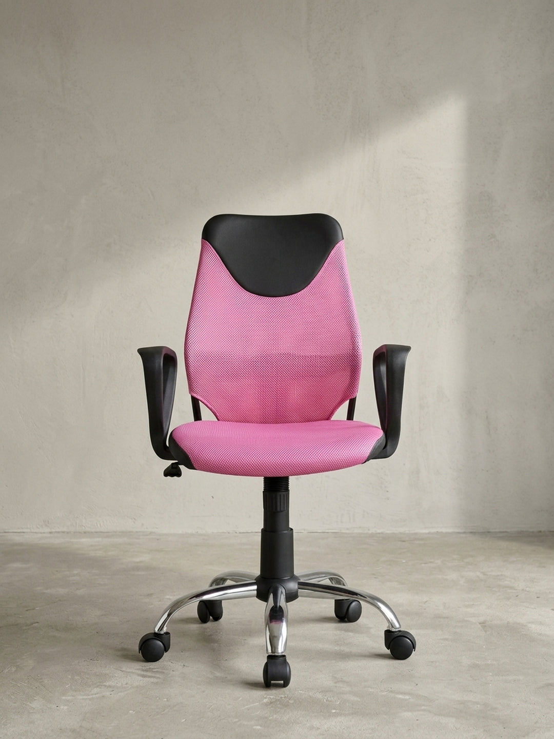 Jugend-Drehstuhl in Pink und Schwarz schräg von vorne gesehen, die geschwungene, ergonomische Rückenlehne auf neutralem Hintergrund._