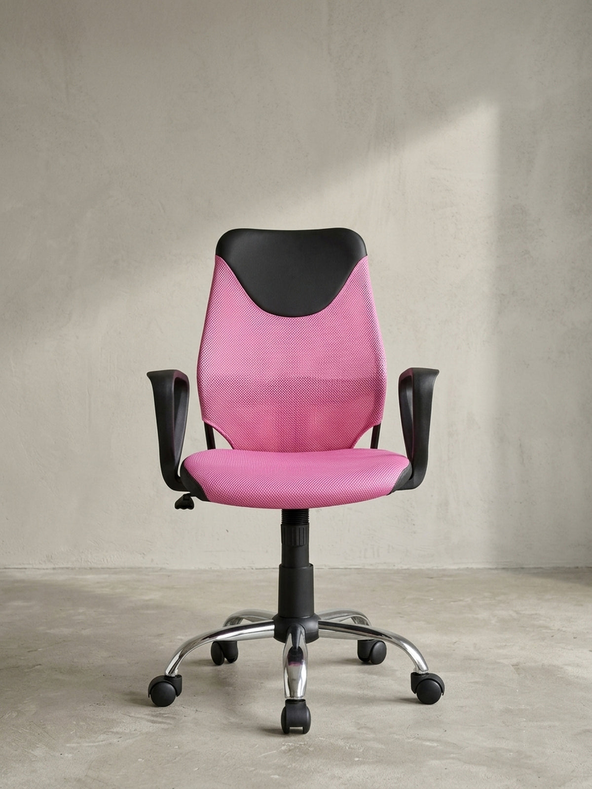 Jugend-Drehstuhl in Pink und Schwarz schräg von vorne gesehen, die geschwungene, ergonomische Rückenlehne auf neutralem Hintergrund._