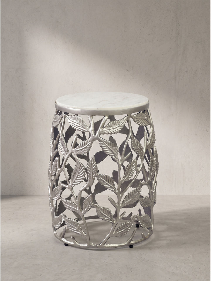 Runder Beistelltisch mit filigranem Blattmotiv-Gestell aus lackiertem Aluminium und weißer Natursteinplatte frontal freigestellt vor weißem Hintergrund._