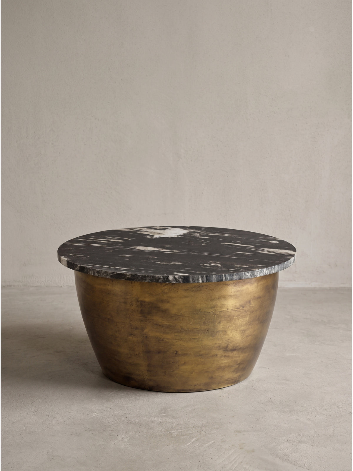 Moderner Beistelltisch in eleganter Trommelform mit patiniertem Gold-Finish und individueller dunkler Natursteinplatte in seitlicher Studioaufnahme