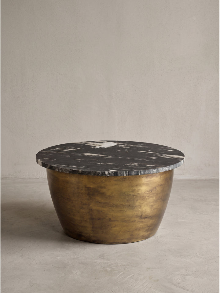 Moderner Beistelltisch in eleganter Trommelform mit patiniertem Gold-Finish und individueller dunkler Natursteinplatte in seitlicher Studioaufnahme_