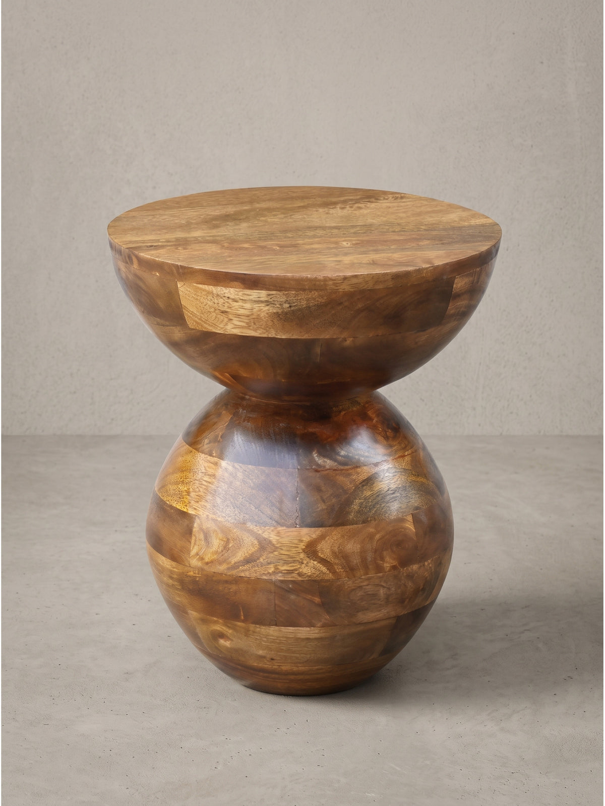 Runder Anstelltisch aus Massivholz Mango 35 cm Durchmesser in leicht angewinkelter Perspektive, die die eleganten Rundungen architektonisch betont