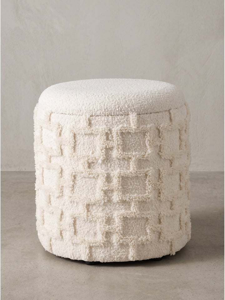 Detailansicht der texturierten Stoffoberfläche und der verdeckten Deckelfuge des runden Sitzhockers in Creme._