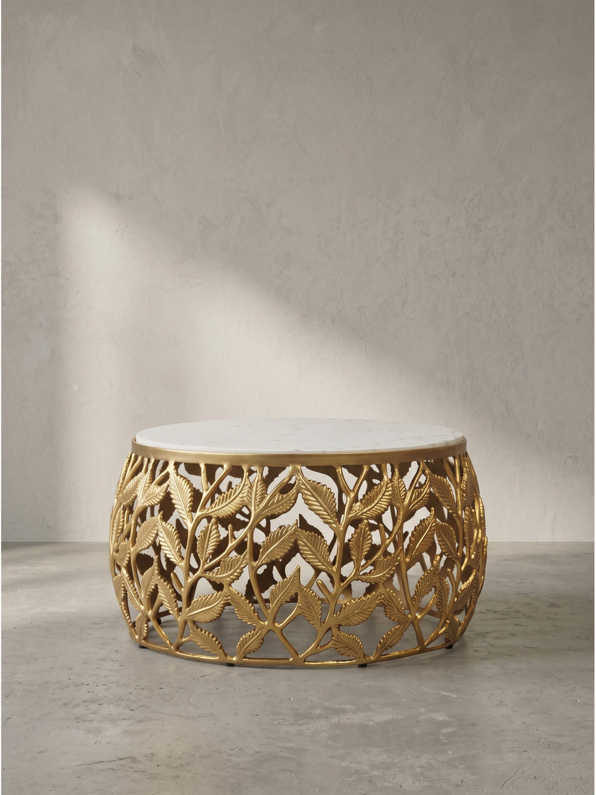 Vorderansicht des 60cm breiten runden Couchtischs mit filigranem goldenen Aluminiumgestell und kühler weißer Naturmarmorplatte_