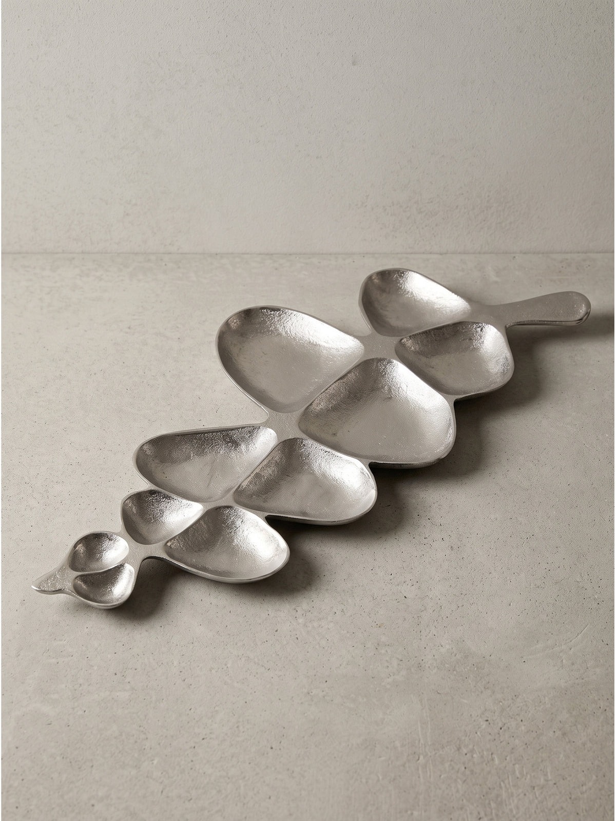 Skulpturale Dekoschale aus silbernem Aluminium 61x18 cm in geschwungener Blattform mit sanften Mulden freigestellt auf weißem Hintergrund